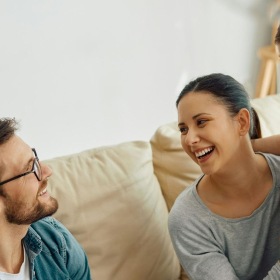 A family sitting on a couch and laughing.
