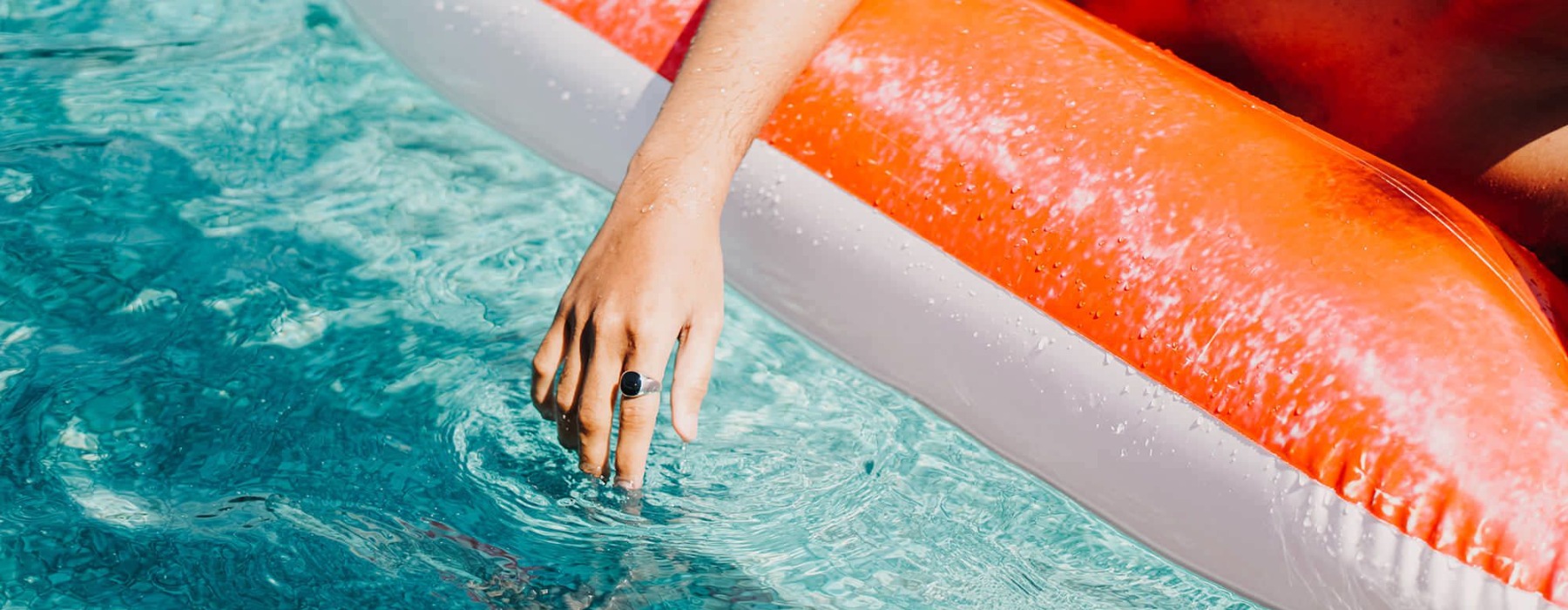 woman dangles her hand in the pool as she floats in an inflatable vessel